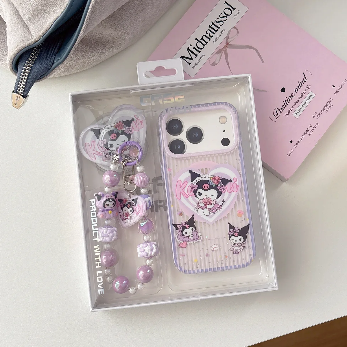 A purple and clear phone case with a heart-shaped pop socket and Kuromi design, shown with a beaded strap.